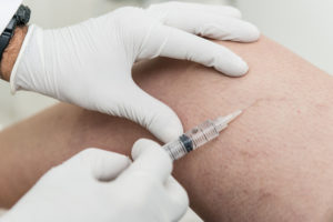 A doctor performing Sclerotherapy on a patients thigh to treat veins.