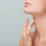 cropped view of woman touching neck isolated on grey