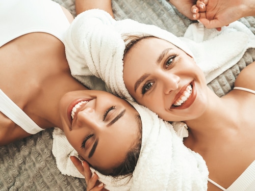 Two,Young,Beautiful,Smiling,Women,In,White,Bathrobes,And,Towels